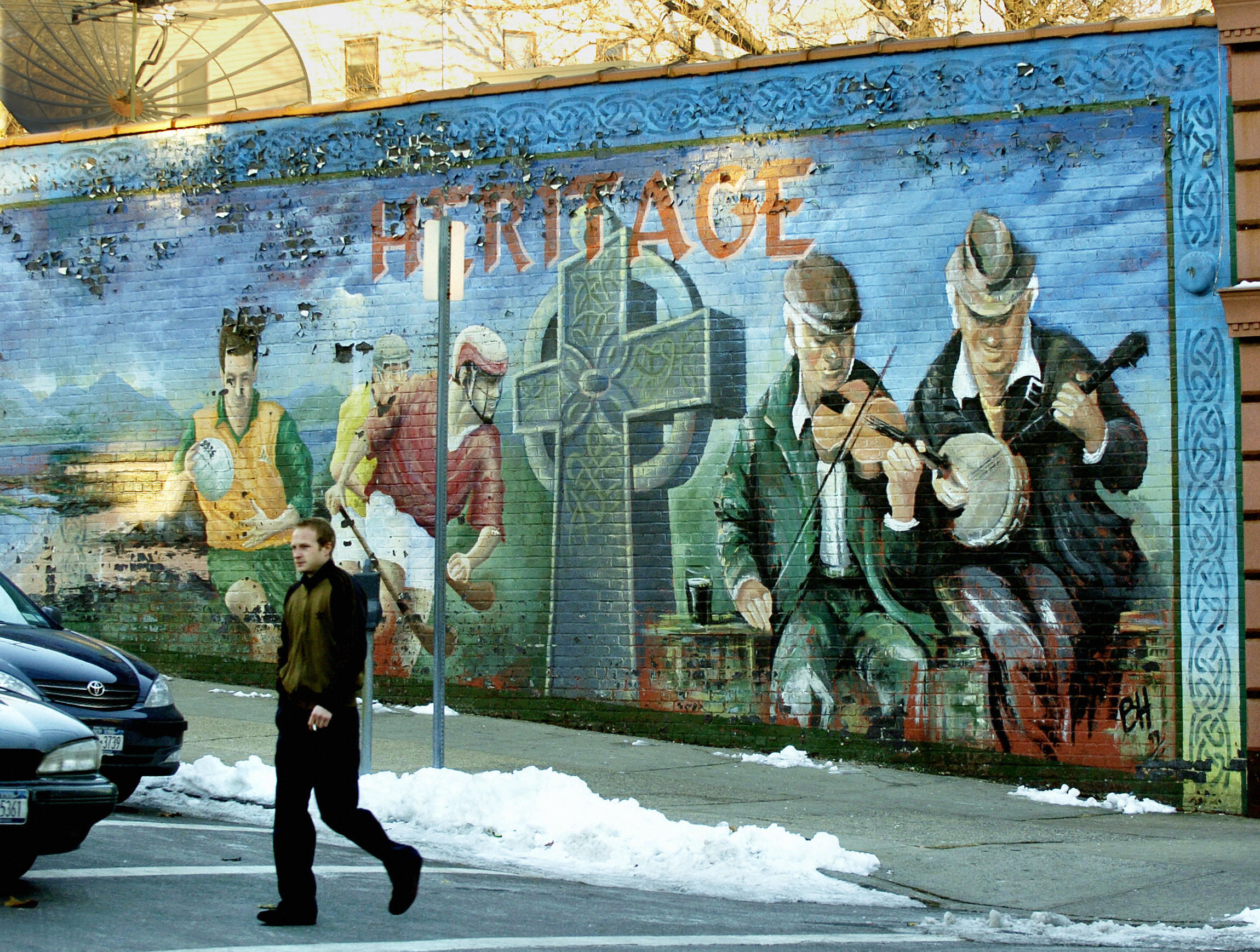 A man walks past a mural showing various scenes from Irish life in Yonkers, New York.