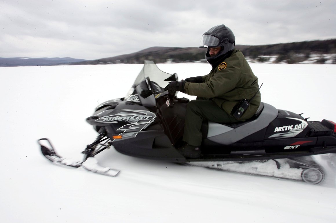 A U.S. Border Patrol Agent rides a snowmobile during a patrol on a frozen lake that splits the Canadian territory behind him and the U.S., near Norton, Vermont.