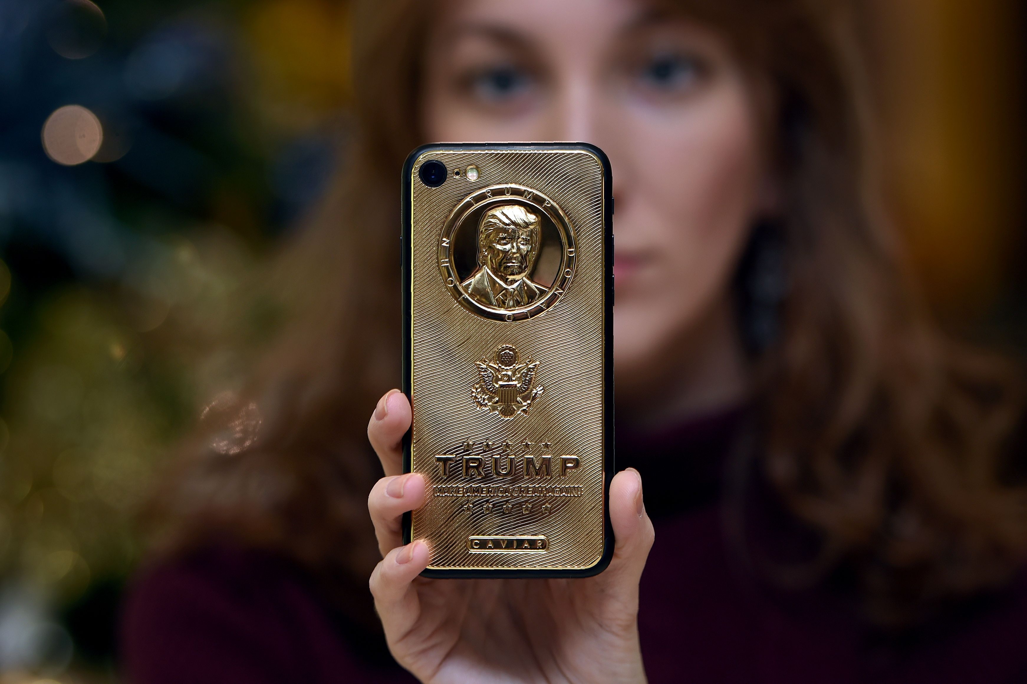 An employee of Caviar Phones, a Russian-Italian company specializing in smartphone customization, displays a special gold-plated iPhone 7 smartphone bearing the likeness of President Donald Trump.