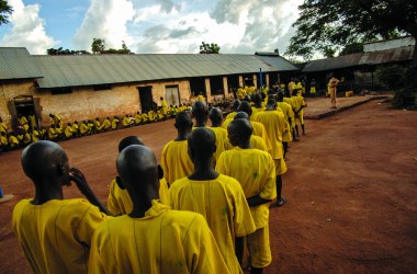 Prisoners, many of whom claim to be juveniles, line up for dinner at Lira Prison, Poor birth records make it difficult for Ugandan prison officials to remove younger prisoners from adult facilities.