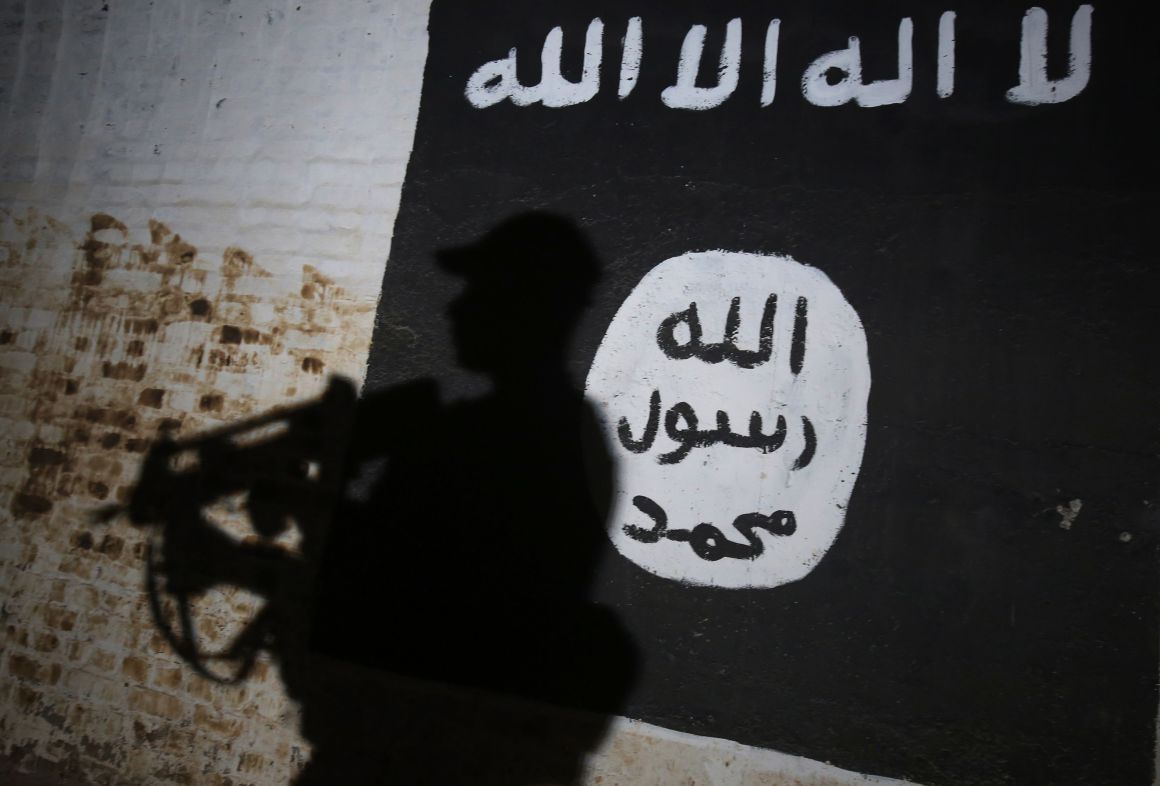 A member of the Iraqi forces walks past a mural bearing the logo of the Islamic State group in a tunnel.