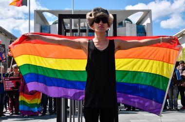 An activist displays a rainbow flag in front of the Chancellery in Berlin on April 30th, 2017, during a demonstration calling for an end to the persecution of gay men in Chechnya.