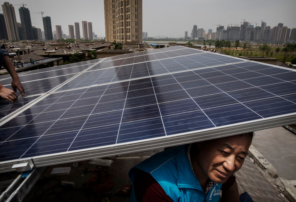 Chinese workers from the Wuhan Guangsheng Photovoltaic Company install solar panels on the roof of a building in Wuhan, China, on April 27th, 2017.