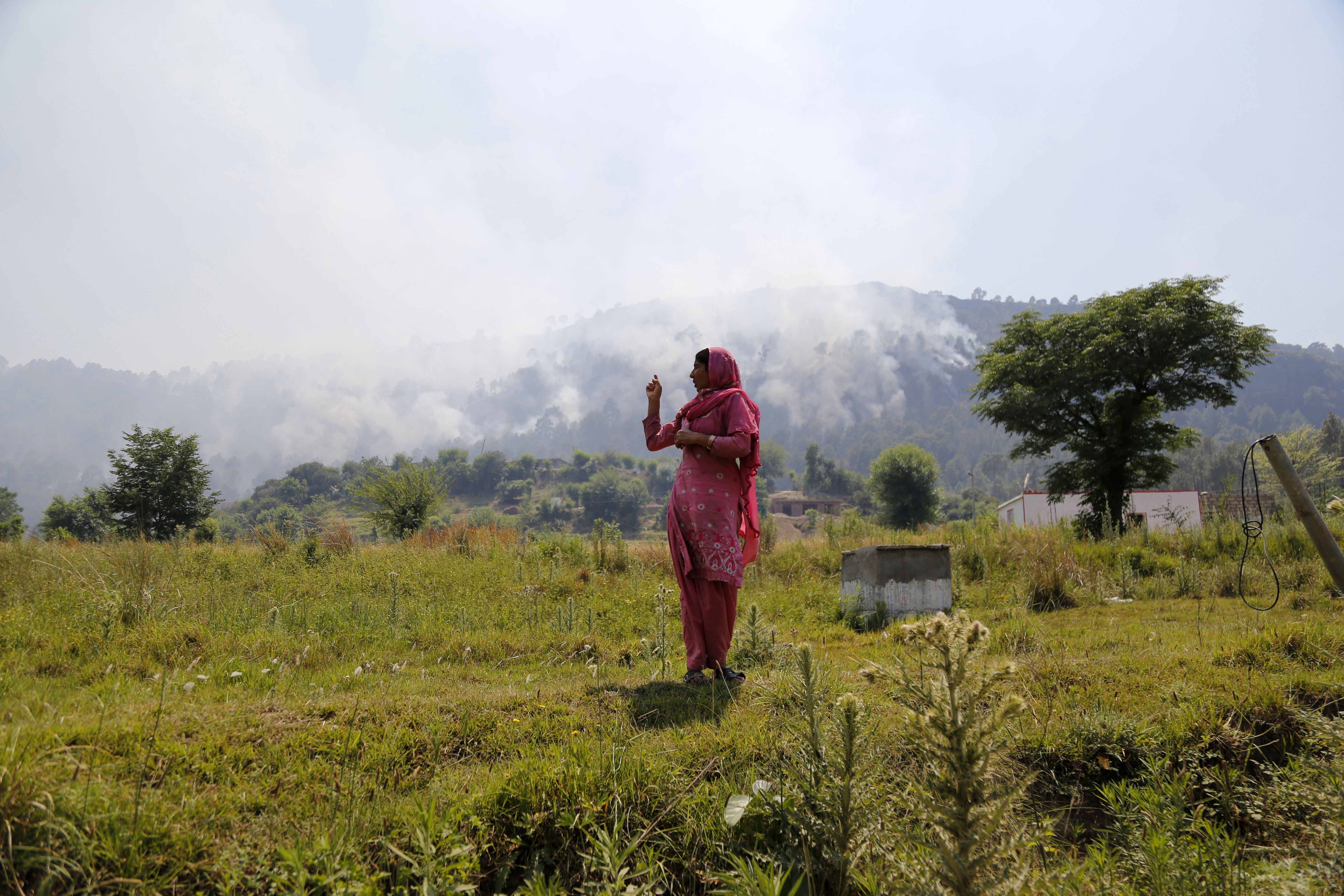 An Indian resident gestures toward rising smoke, believed to have resulted from mortar shelling, in the village of Jhangar, which lies very close to Pakistan on the Line of Control, on May 14th, 2017.