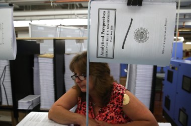 Government worker Laurie Ridgley watches as Office of Management and Budget Director Mick Mulvaney tours the binding facility where President Donald Trump's FY'18 budget books are being produced, at the Government Publishing Office, on May 19th, 2017.