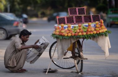 A fruit vendor reads a newspaper as he waits for customers on a street in Islamabad, Pakistan, on May 23rd, 2017.