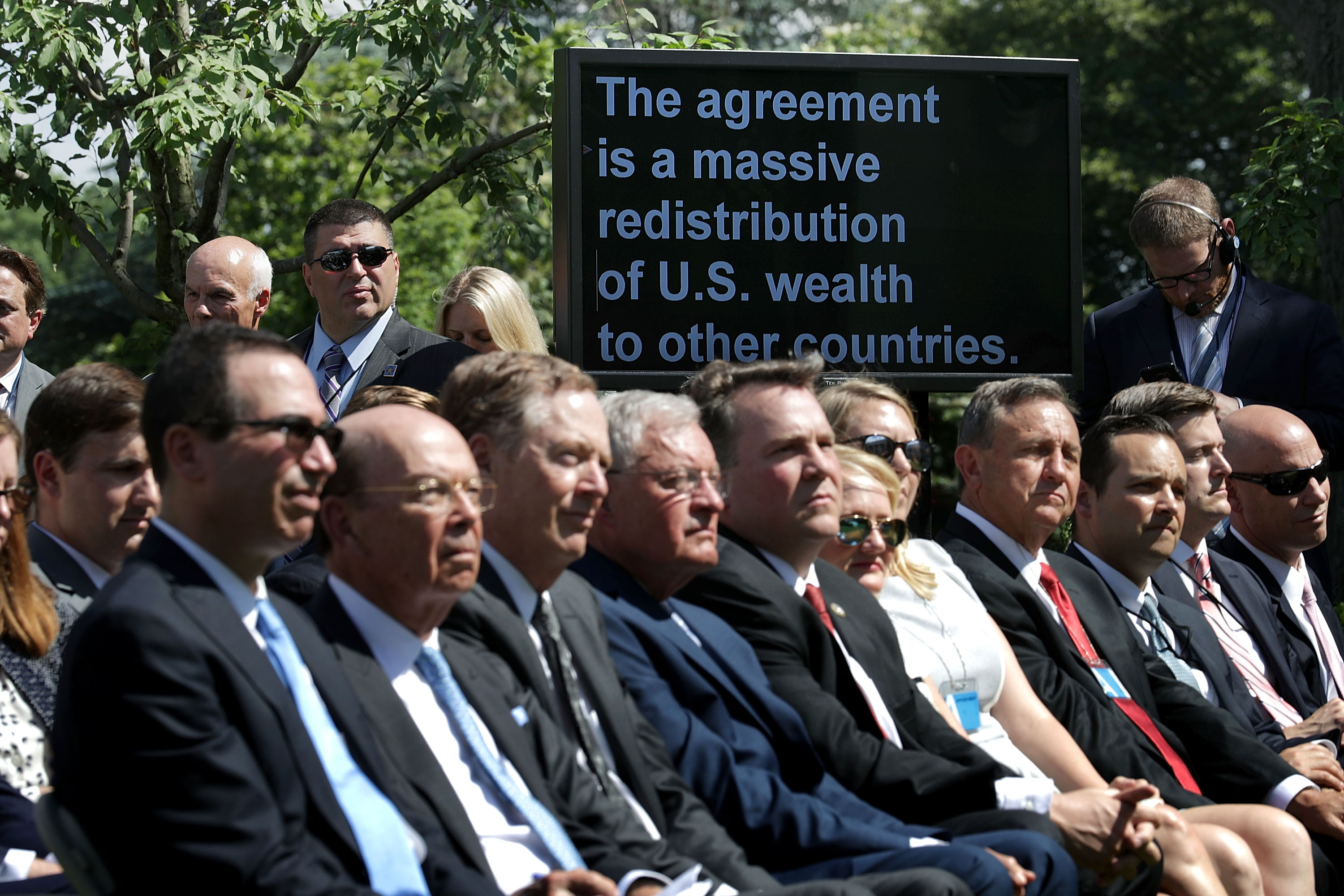 President Donald Trump's remarks appear on a television monitor as members of his administration and invited guests listen to him announce the decision to pull out of the Paris climate agreement at the White House on June 1st, 2017.