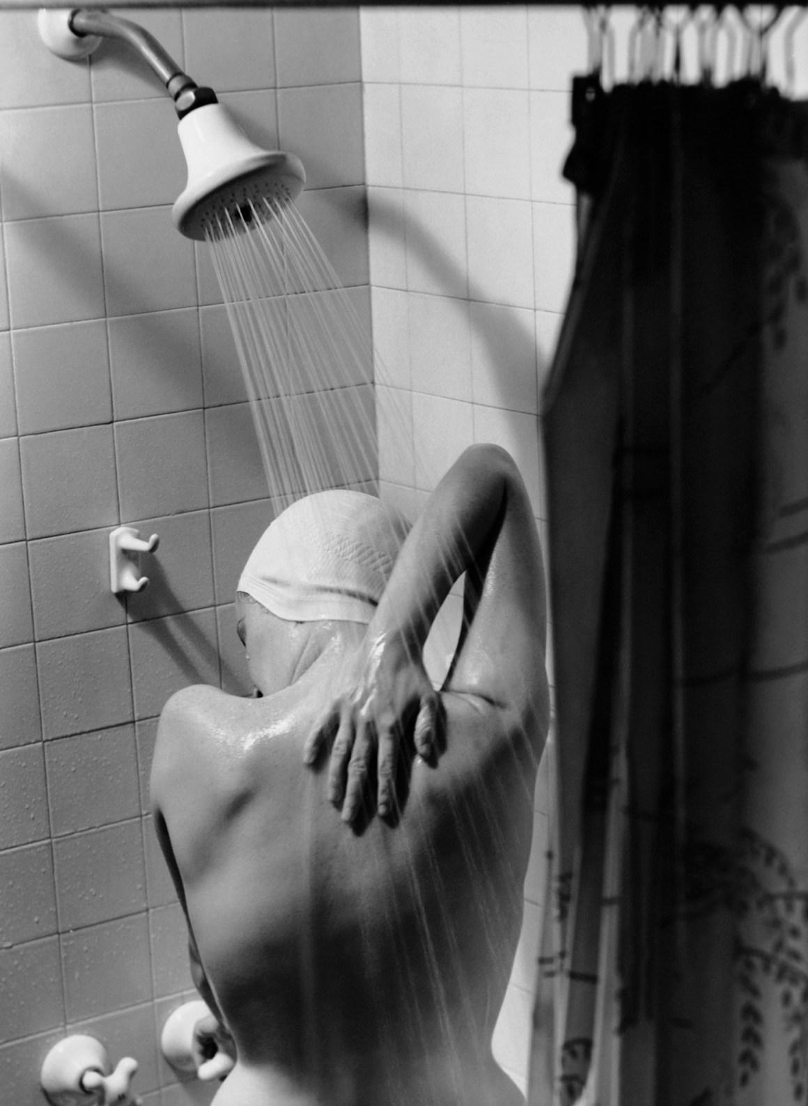 A woman takes a shower circa 1950.