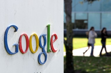 People walk near a sign outside of Google headquarters.