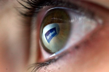 In this photo illustration the Facebook logo is reflected in the eye of a girl.