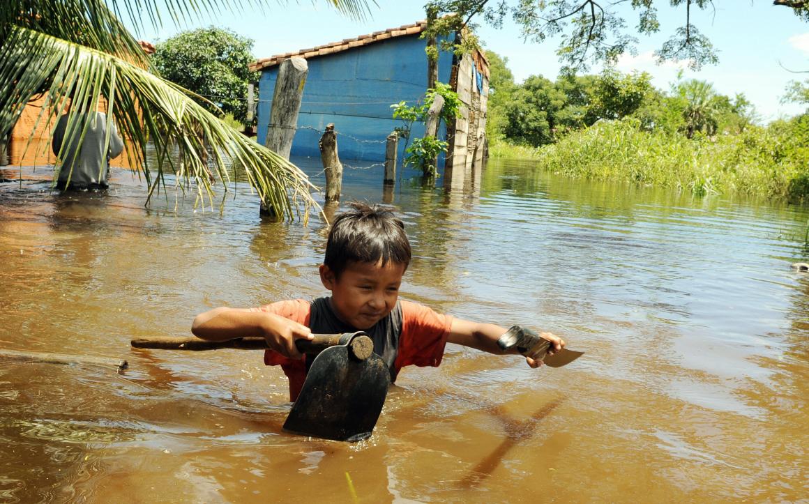 Bolivian boy Pedrito Arce wades through the water carrying some of his family's belongings in the flooded hamlet of Los Bibosi.