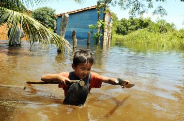 Bolivian boy Pedrito Arce wades through the water carrying some of his family's belongings in the flooded hamlet of Los Bibosi.