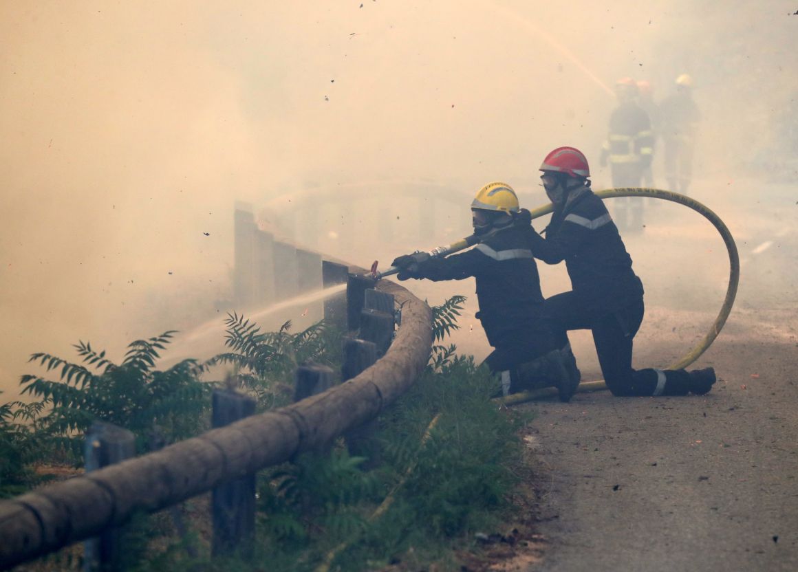 Firefighters use a hose to spray water as they fight against a fire in Castagniers, France, on July 17th, 2017.