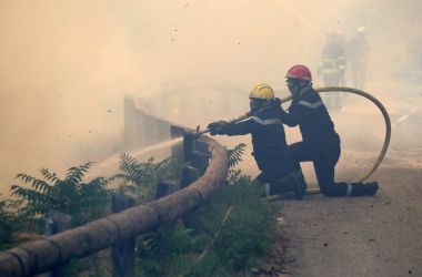 Firefighters use a hose to spray water as they fight against a fire in Castagniers, France, on July 17th, 2017.