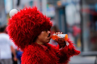 A man dressed as Elmo drinks to keep hydrated at Times Square during a sunny day as hot temperatures continue in New York on July 21st, 2017.