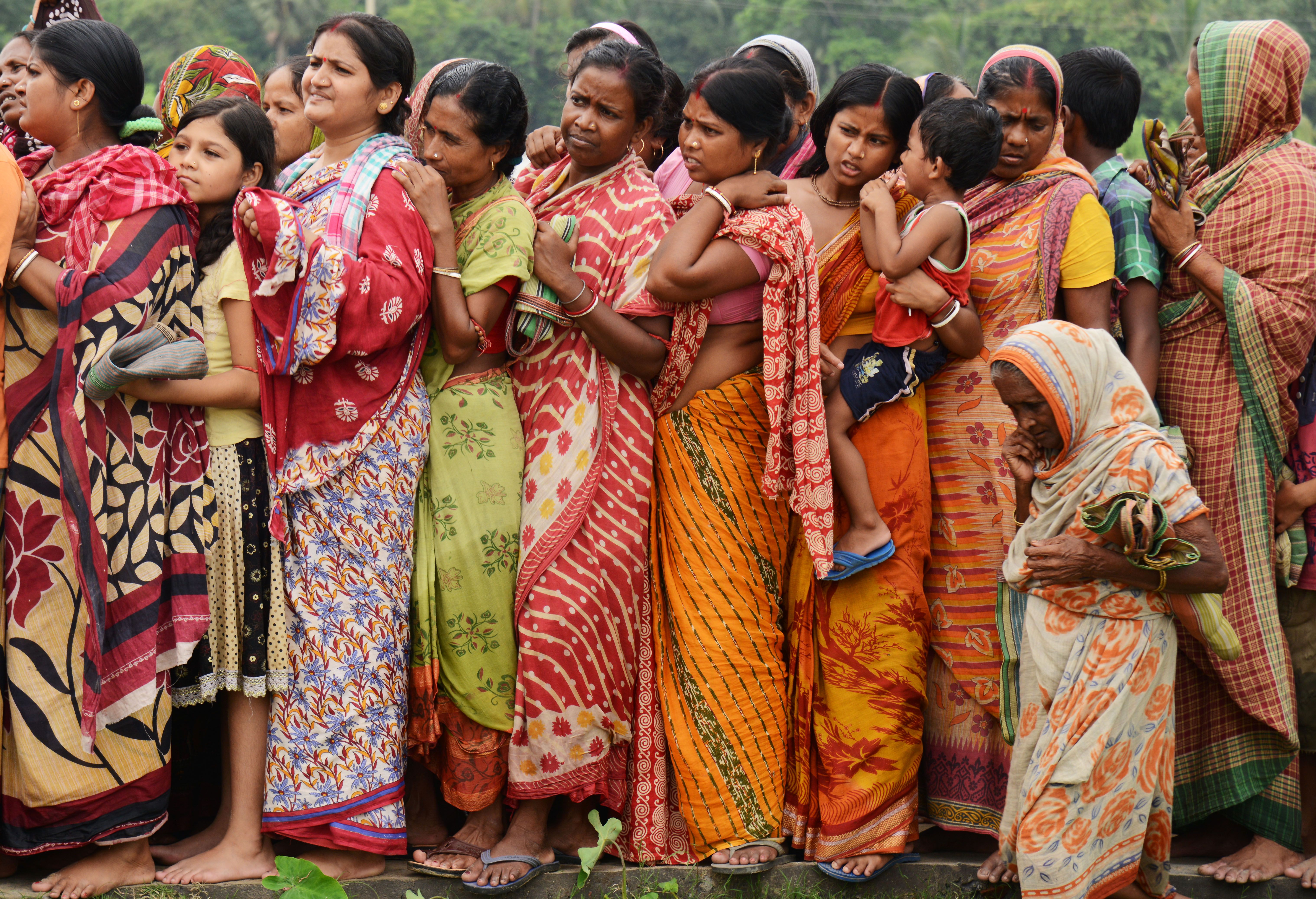 Indian flood victims wait in a queue to collect relief materials in Chitnan village, around 60 km West of Kolkata, on July 28, 2017. The Indian Meteorological Department (IMD) has issued warnings of heavy rains across Gujarat state of Western India in next 24 hours.