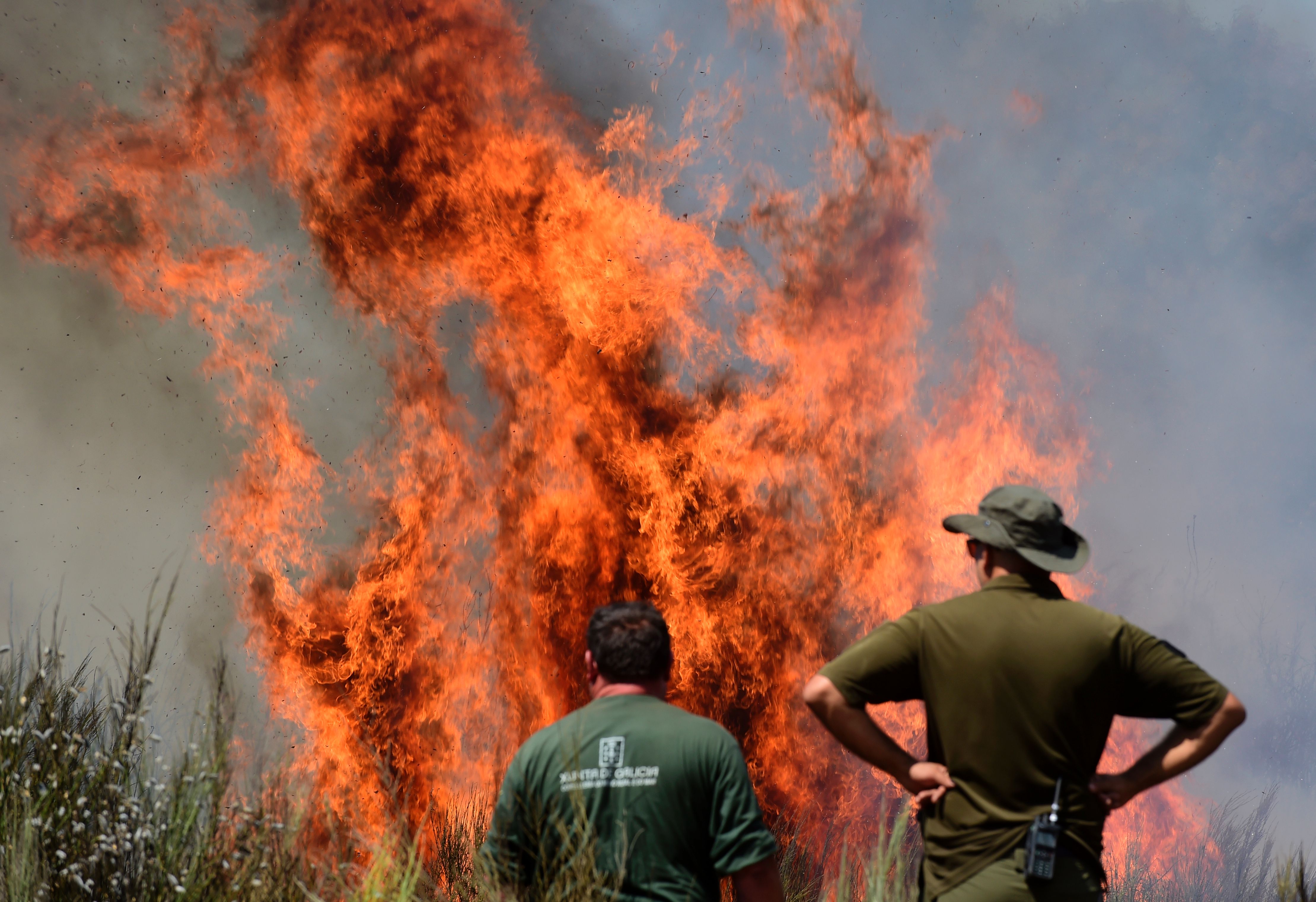 Members of a firefighting brigade stand close to a wildfire in Vilardevos, next to Verin, northwestern Spain, on August 4th, 2017.