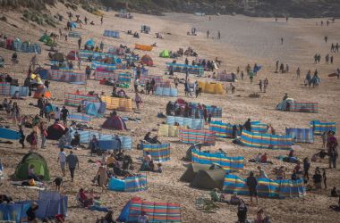 People gather on Fistral beach as surfers compete in a heat of the World Surf League Boardmasters Quicksilver Open at the annual Boardmasters festival on August 9th, 2017, in Cornwall, England. Since 1981, the Boardmasters surfing competition has been held in Newquay and is now part of a larger five-day surf, skate, and music festival. It attracts professional surfers from across the globe to compete on the Cornish beach that is seen by many as the birthplace of modern British surfing.