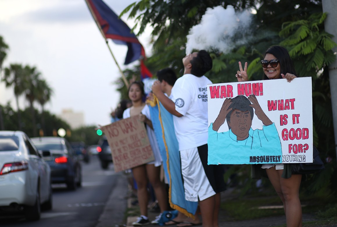 Protesters hold signs during a People for Peace Rally at the Chief Quipuha Statue on August 14th, 2017, in Hagatna, Guam.