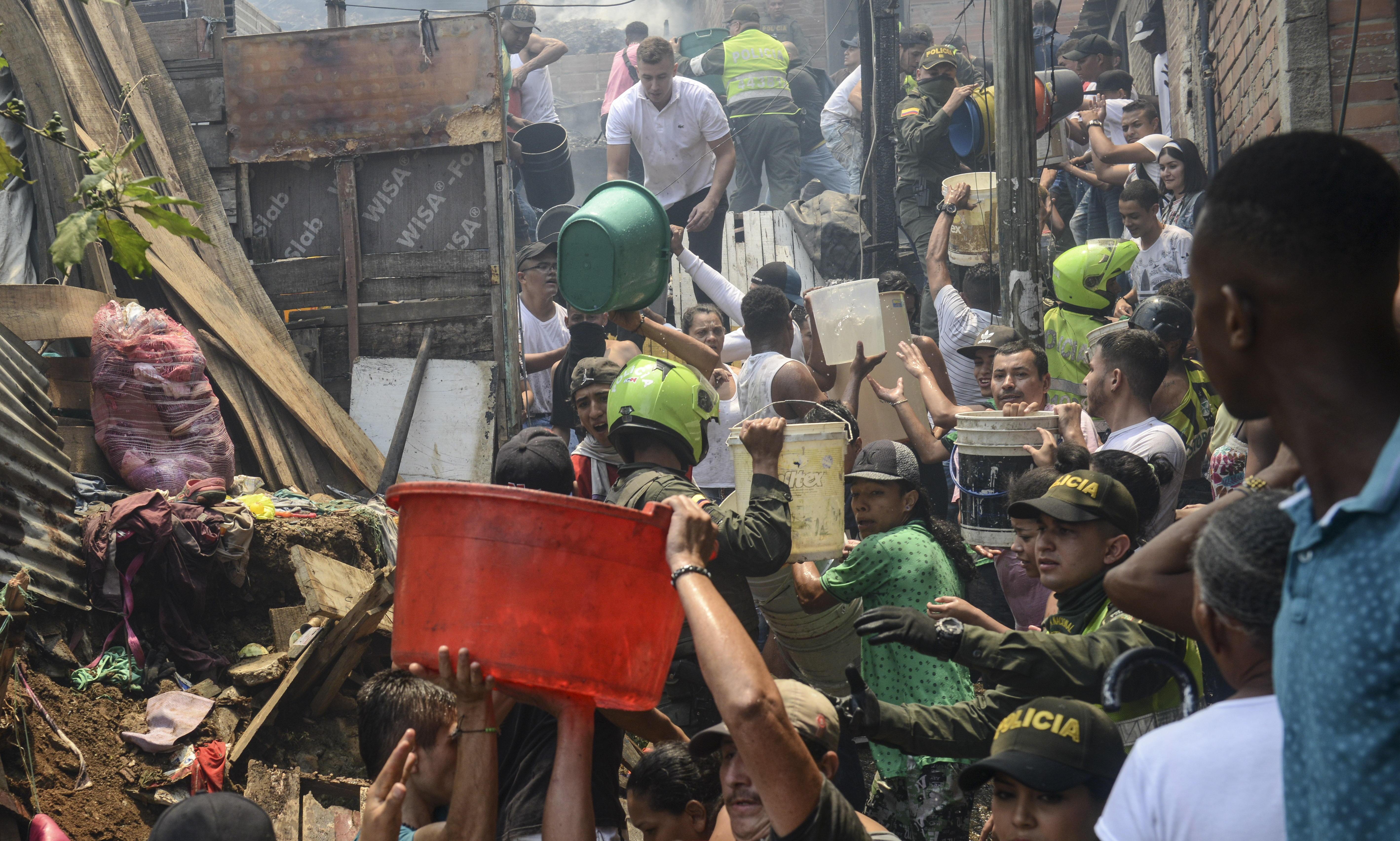 Local residents and policemen fight a huge fire in the Moravia neighborhood in Medellin on August 18th, 2017. The Moravia sector is known for having been built on a garbage dump and for being the base for late drug lord Pablo Escobar's first political campaign and where he helped to build a football field and to install the electric network.