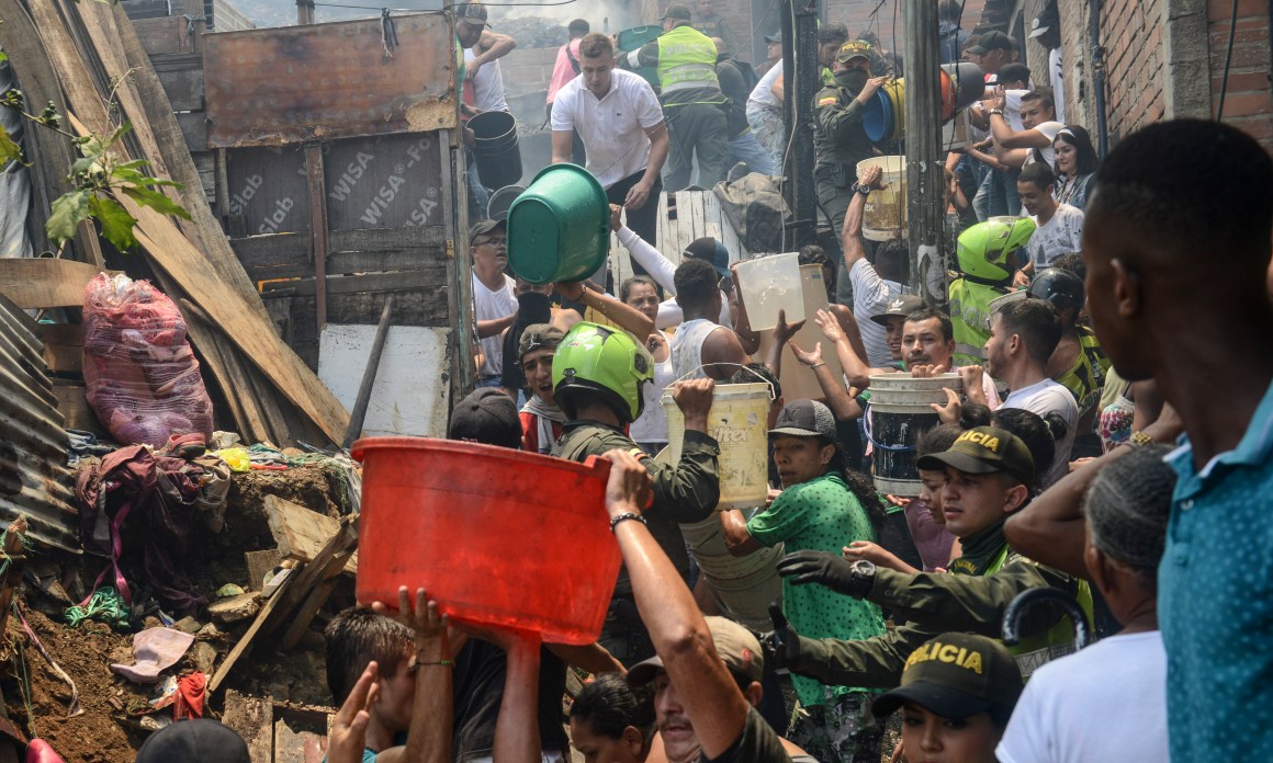 Local residents and policemen fight a huge fire in the Moravia neighborhood in Medellin on August 18th, 2017. The Moravia sector is known for having been built on a garbage dump and for being the base for late drug lord Pablo Escobar's first political campaign and where he helped to build a football field and to install the electric network.