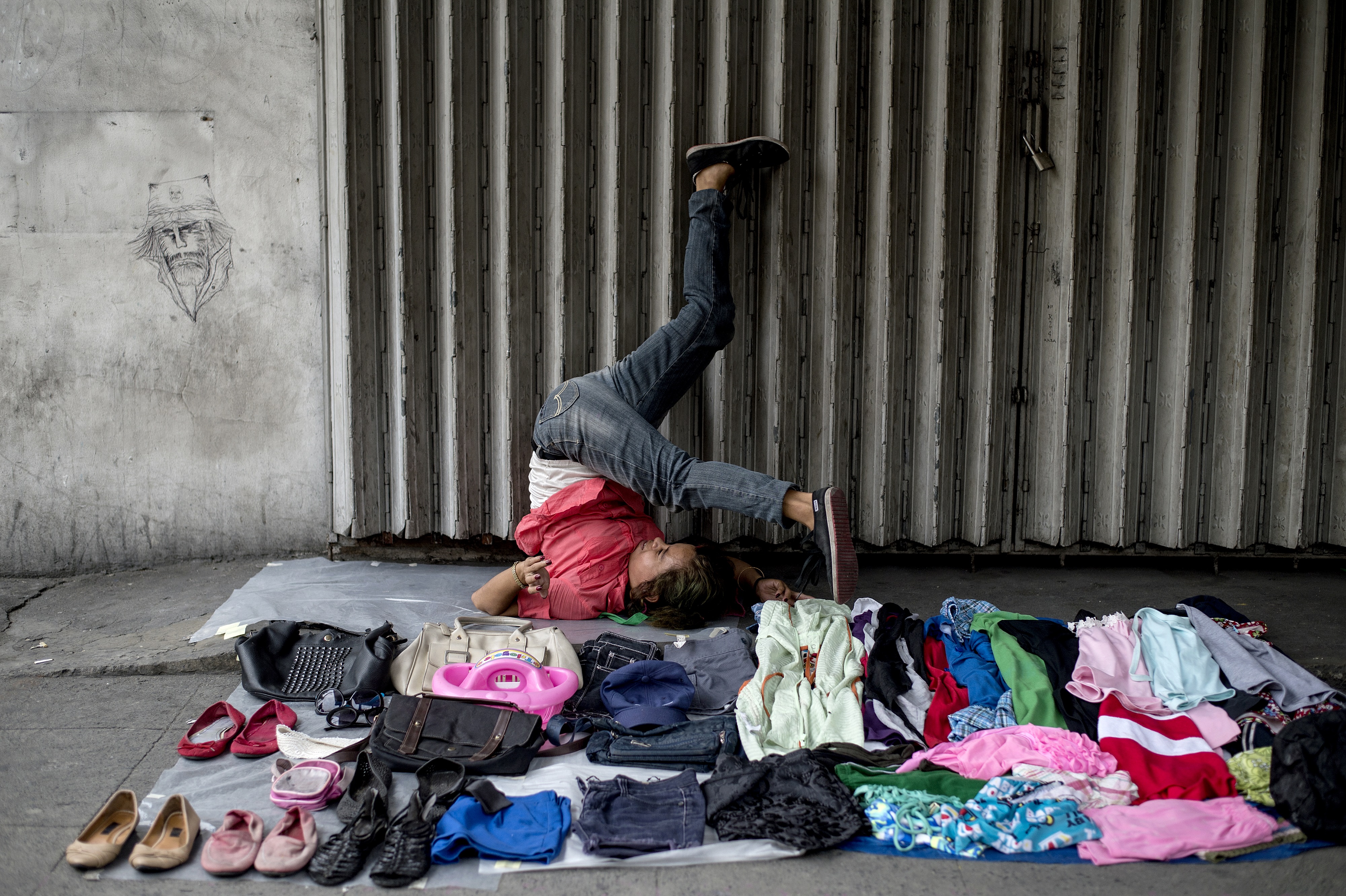 A street vendor stretches as she waits for customers along a street in Manila on August 23rd, 2017.