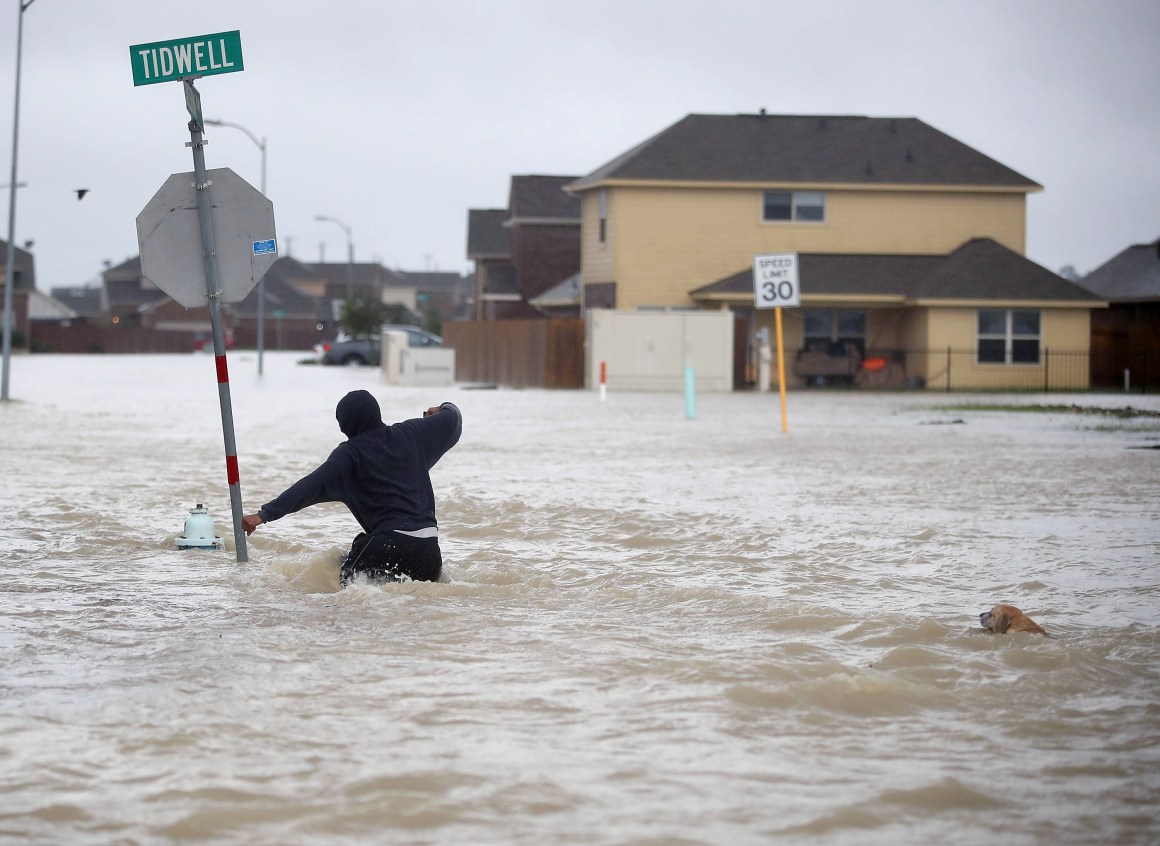 A person walks through a flooded street with a dog after the area was inundated with flooding from Hurricane Harvey on August 28th, 2017, in Houston, Texas.