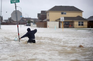 A person walks through a flooded street with a dog after the area was inundated with flooding from Hurricane Harvey on August 28th, 2017, in Houston, Texas.