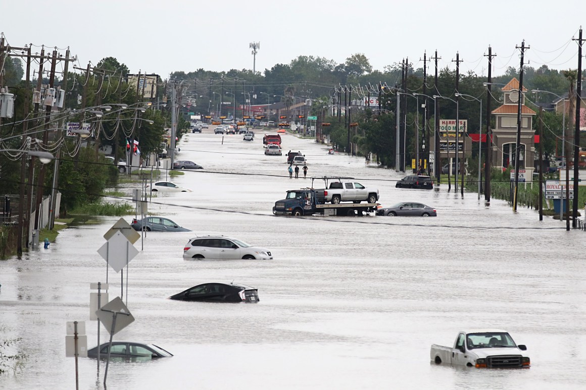 A car gets towed while men walk through a flooded street in Houston, Texas, on August 30th, 2017.