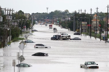 A car gets towed while men walk through a flooded street in Houston, Texas, on August 30th, 2017.