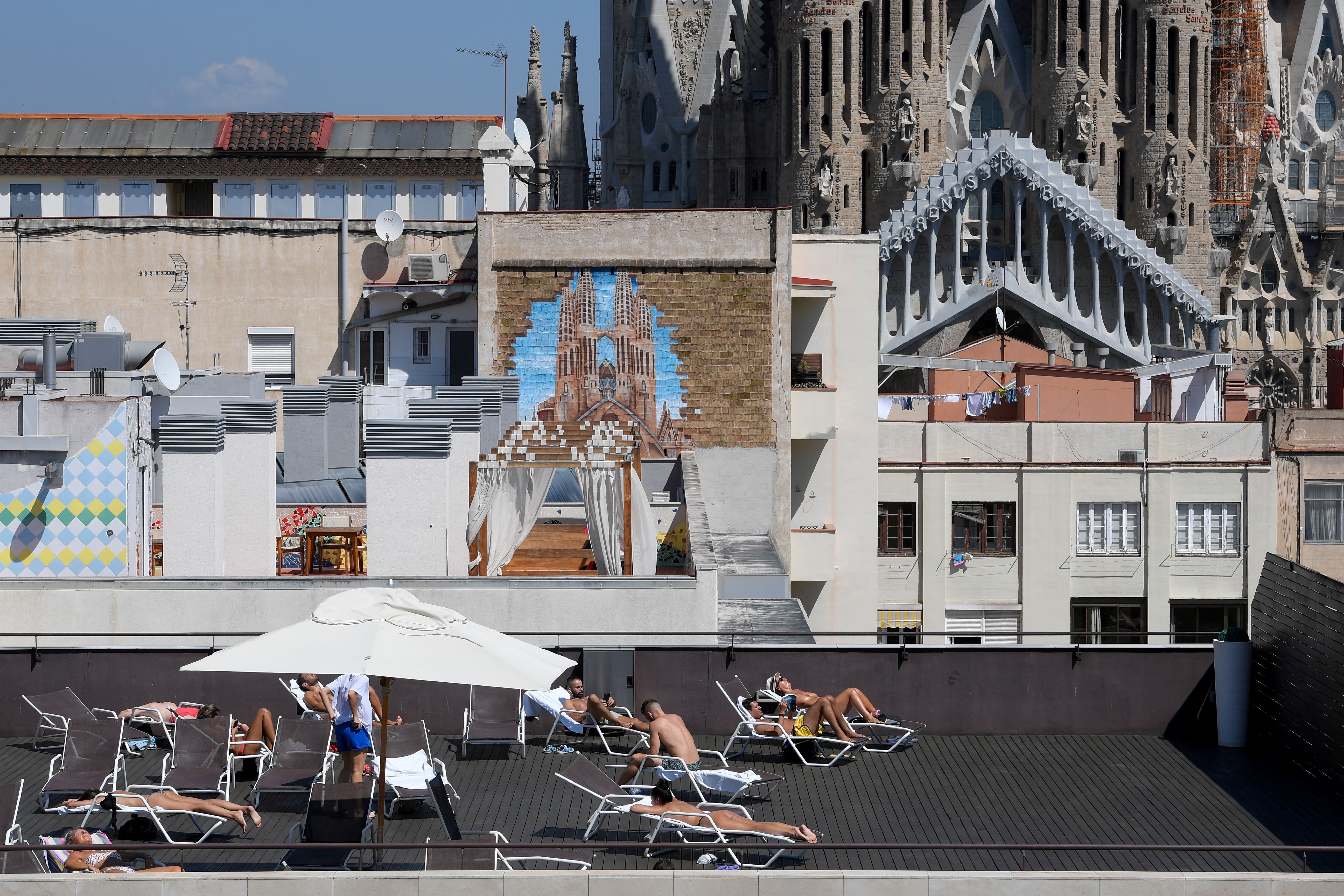 Tourists sunbathe on the terrace of an hotel with the Sagrada Familia in the background in Barcelona, Spain, on September 5th, 2017.