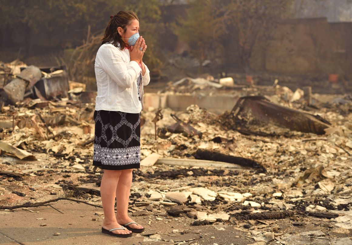 A woman looks at the wreckage of her burned home in Santa Rosa, California, on October 10th, 2017. Firefighters were battling 17 large wildfires, which have left at least 13 people dead, thousands homeless, and ravaged the state's wine country.