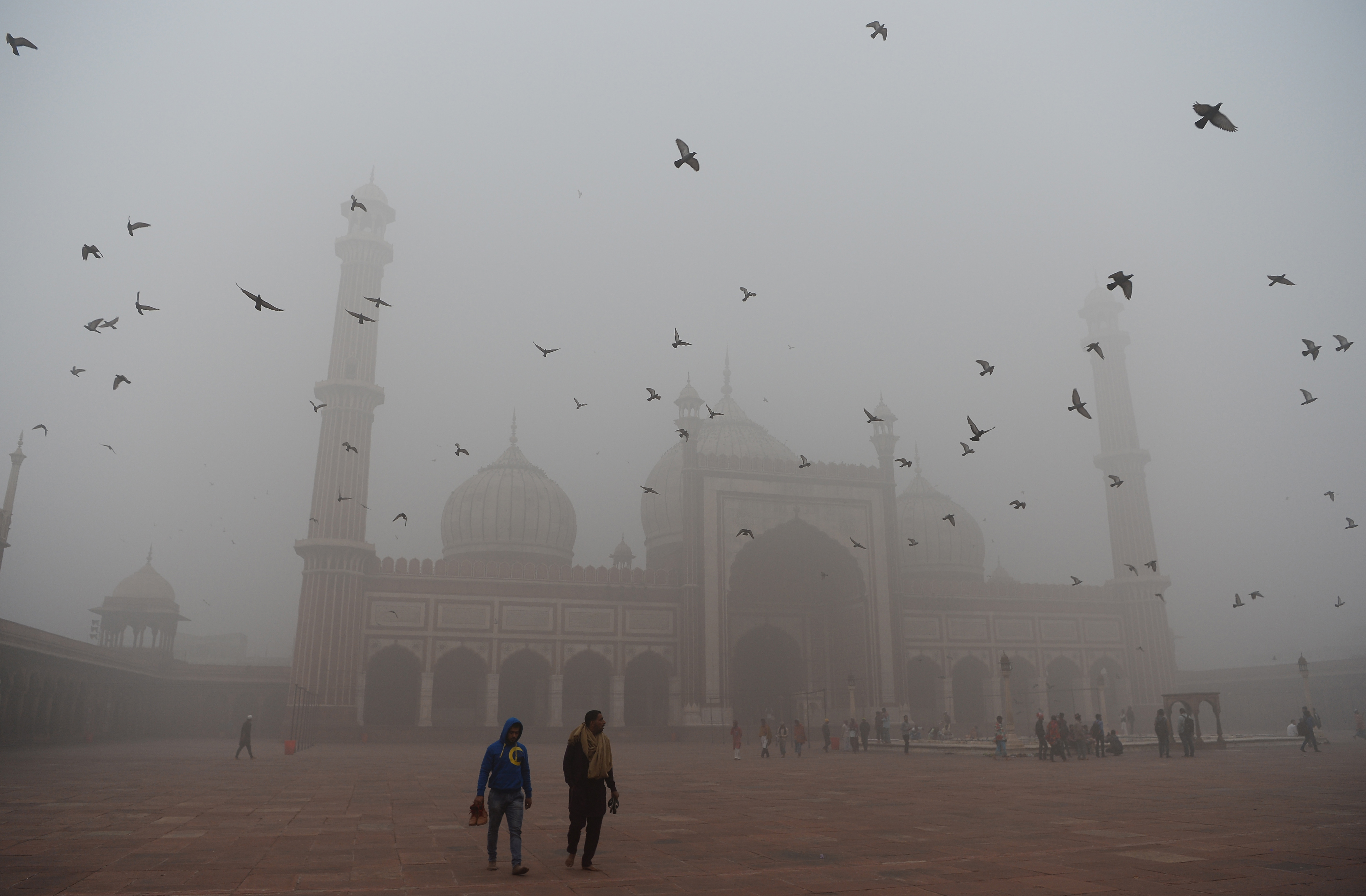 Indian visitors walk through the courtyard of the Jama Masjid mosque amid heavy smog in the old quarters of New Delhi on November 8th, 2017. The city's pollution levels hit nearly 30 times the World Health Organization safe level on Wednesday.