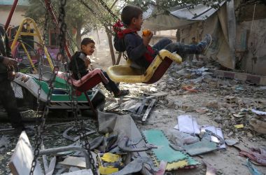 Syrian boys swing on the playground outside their damaged school on November 9th, 2017, in the besieged rebel-held Eastern Ghouta town of Hamouriyah, following air raids by government forces the previous day.