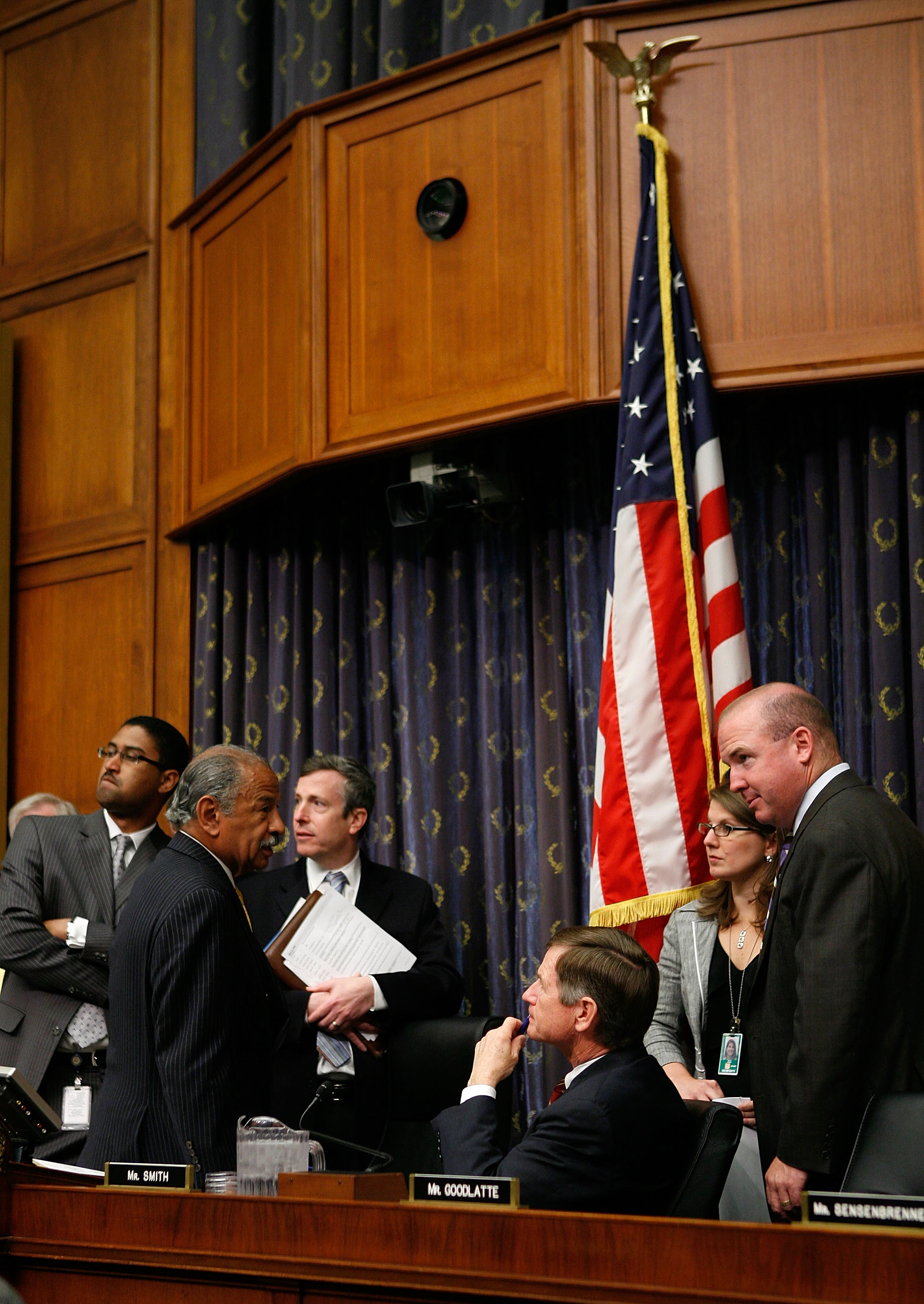 Representative John Conyers (D-Michigan) talks to Representative Lamar Smith (R-Texas) as aides listen prior to a hearing before the House Judiciary Committee on Capitol Hill on May 14th, 2009.