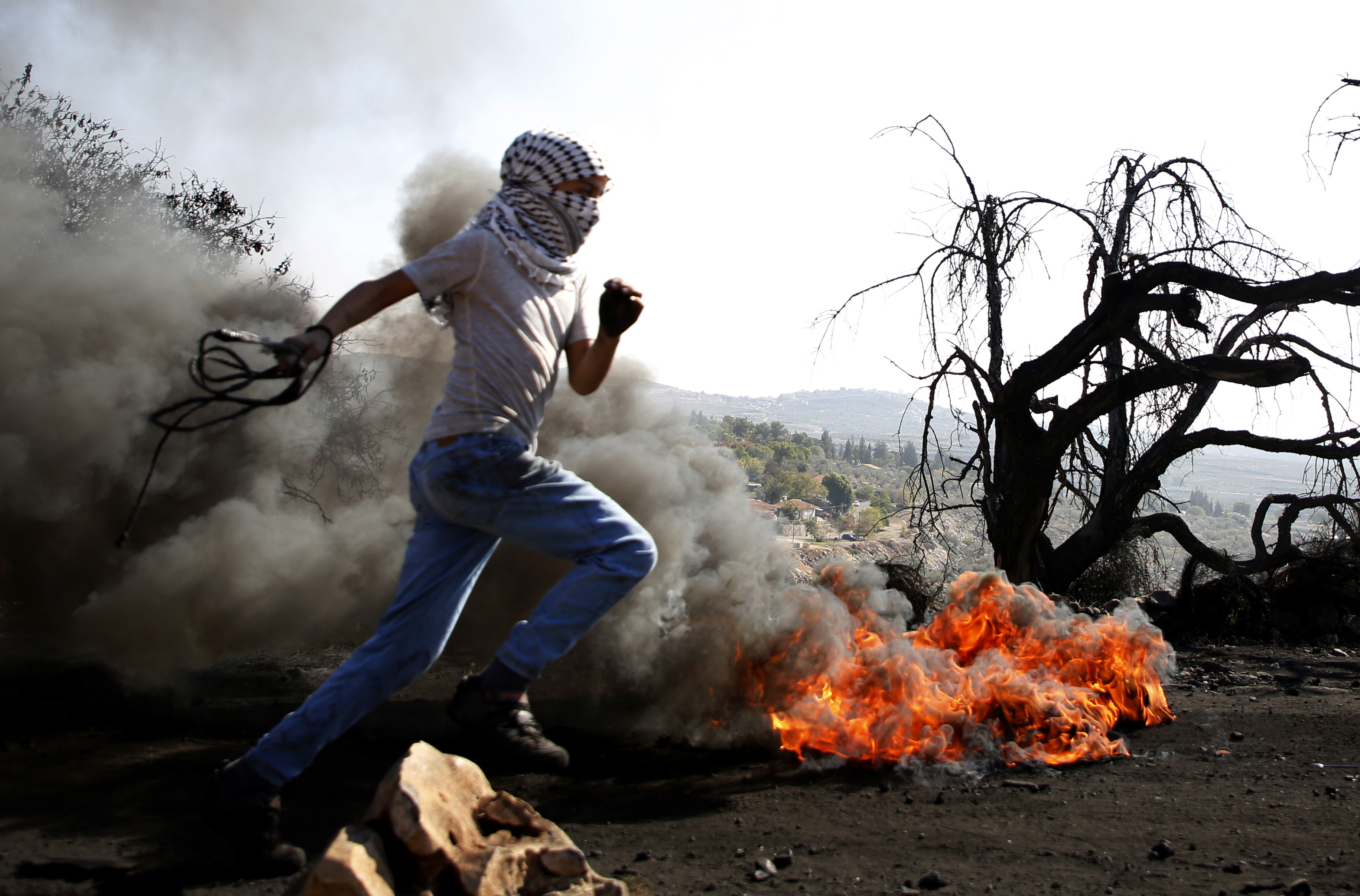 A Palestinian protester runs past burning tires during a clash with Israeli forces over occupation in the village of Kfar Qaddum, near the occupied West Bank, on November 10th, 2017.