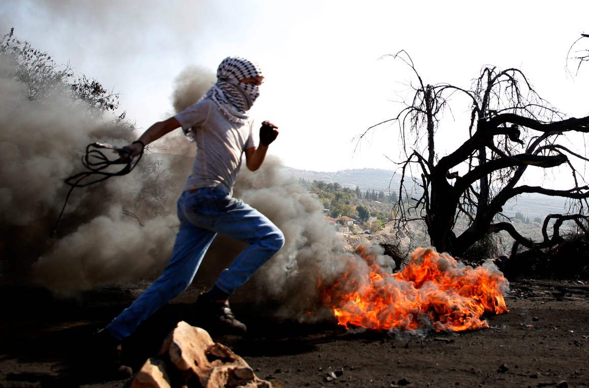 A Palestinian protester runs past burning tires during a clash with Israeli forces over occupation in the village of Kfar Qaddum, near the occupied West Bank, on November 10th, 2017.