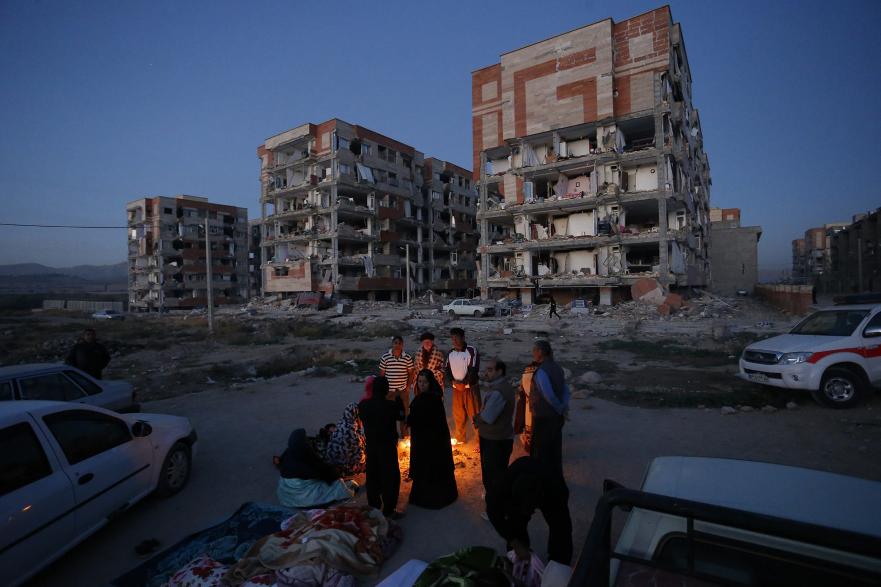 Residents huddle by a fire in an open area in Iran's Kermanshah province on November 13th, 2017.