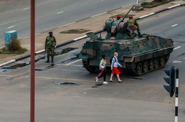 Pedestrians pass a tank stationed at an intersection as Zimbabwean soldiers regulate traffic in Harare on November 15th, 2017. Zimbabwe's military placed President Robert Mugabe under house arrest and took control of the country in an apparent coup on Wednesday.