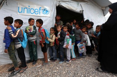 Displaced Iraqi children from the former embattled city of Mosul line up outside a UNICEF school.