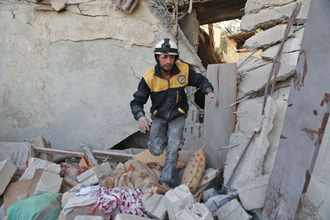 A volunteer from the Syrian Civil Defence searches the rubble of a building following a reported airstrike in the rebel-controlled town of Hamouria on the outskirts of Damascus on November 28th, 2017.