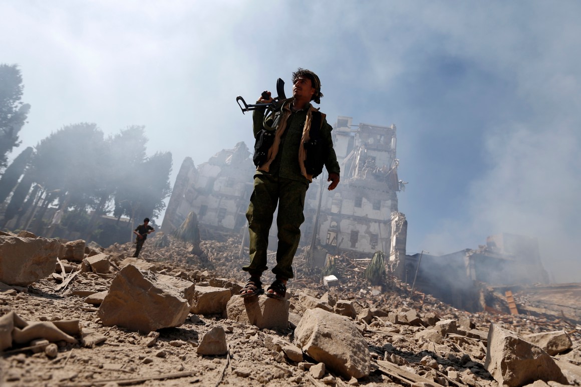 Huthi rebel fighters inspect the damage after a reported air strike carried out by the Saudi-led coalition.