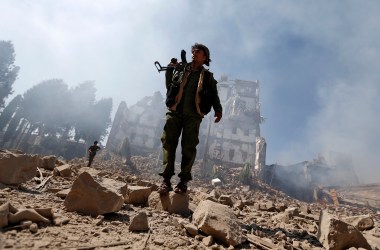 Huthi rebel fighters inspect the damage after a reported air strike carried out by the Saudi-led coalition.