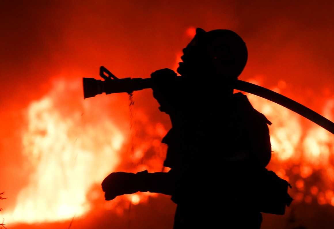 A firefighter battles a wildfire as it burns along a hillside near homes in Santa Paula, California.