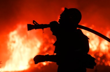 A firefighter battles a wildfire as it burns along a hillside near homes in Santa Paula, California.