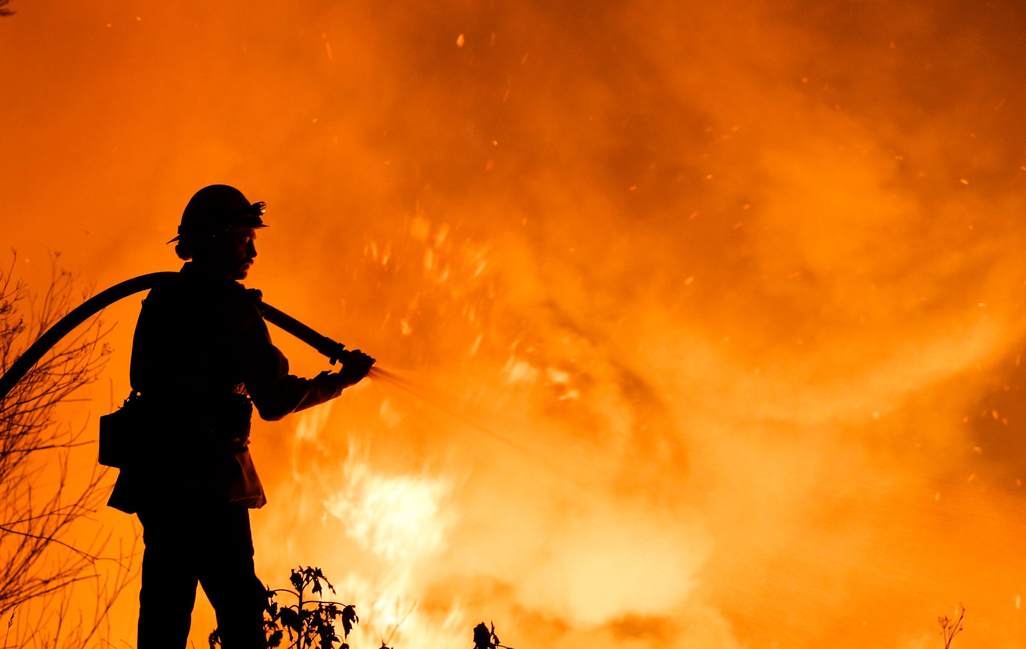 A firefighter battles a wildfire as it burns along a hillside near homes in Santa Paula, California, on December 5th, 2017.