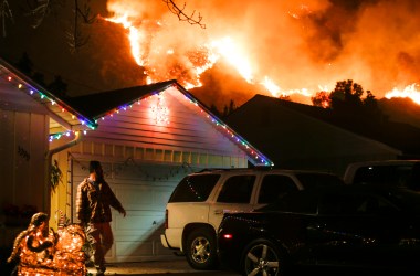 A man prepares to evacuate his home as a wildfire burns along a hillside near homes in Santa Paula, California.