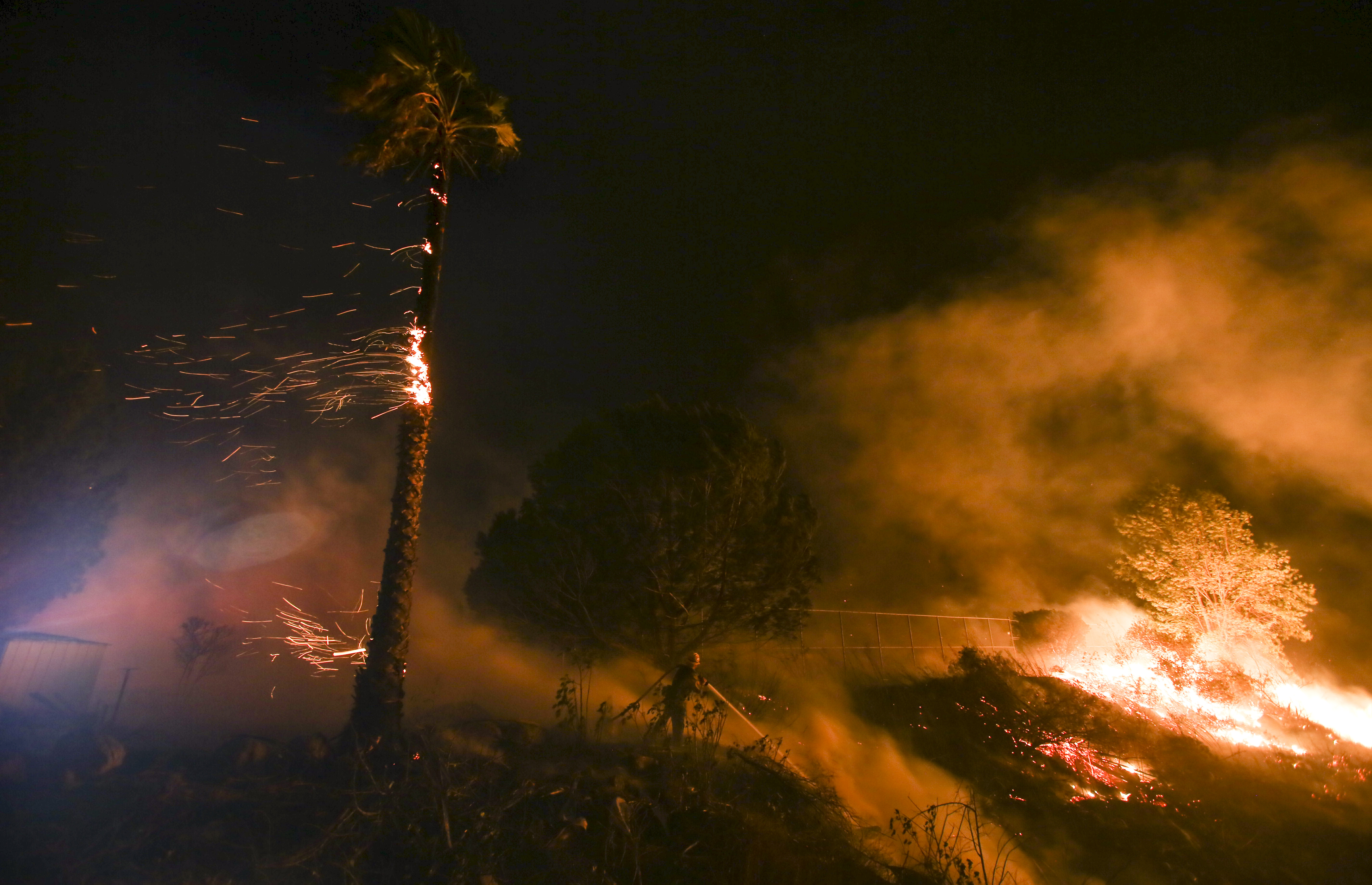 A firefighter battles a wildfire as it burns along a hillside near homes in Santa Paula, California.