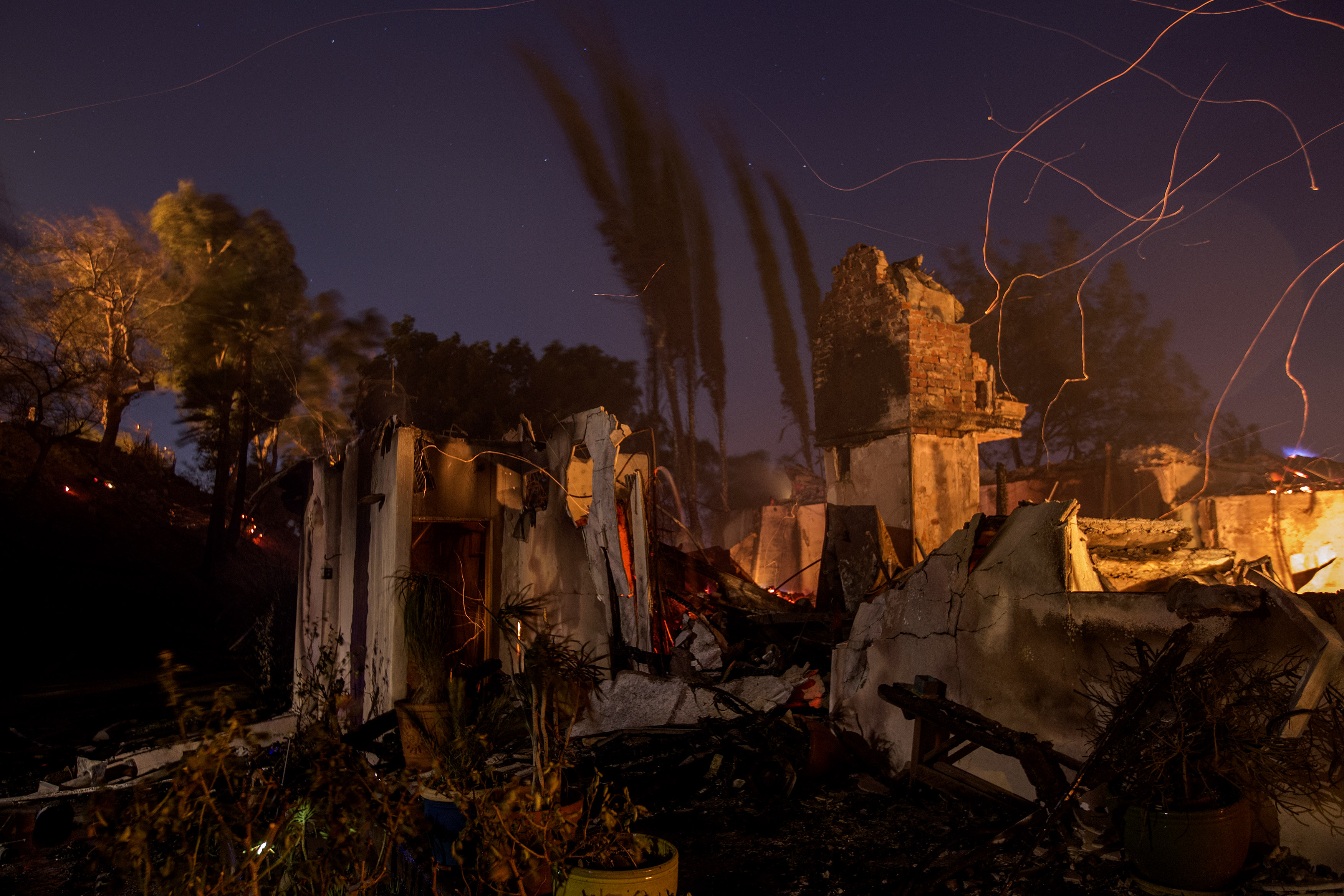 Strong wind blows embers across the smoldering ruins of a house at the Creek Fire in Sunland, California. Strong Santa Ana winds are rapidly pushing multiple wildfires across the region, expanding across tens of thousands of acres and destroying hundreds of homes and structures.