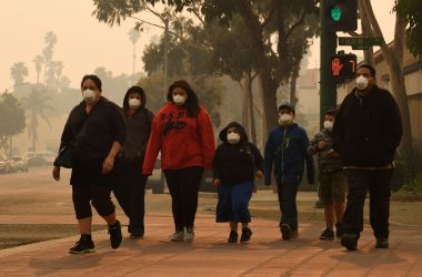 A family wears face masks as they walk through the smoke-filled streets of Ventura, California, on December 6th, 2017.